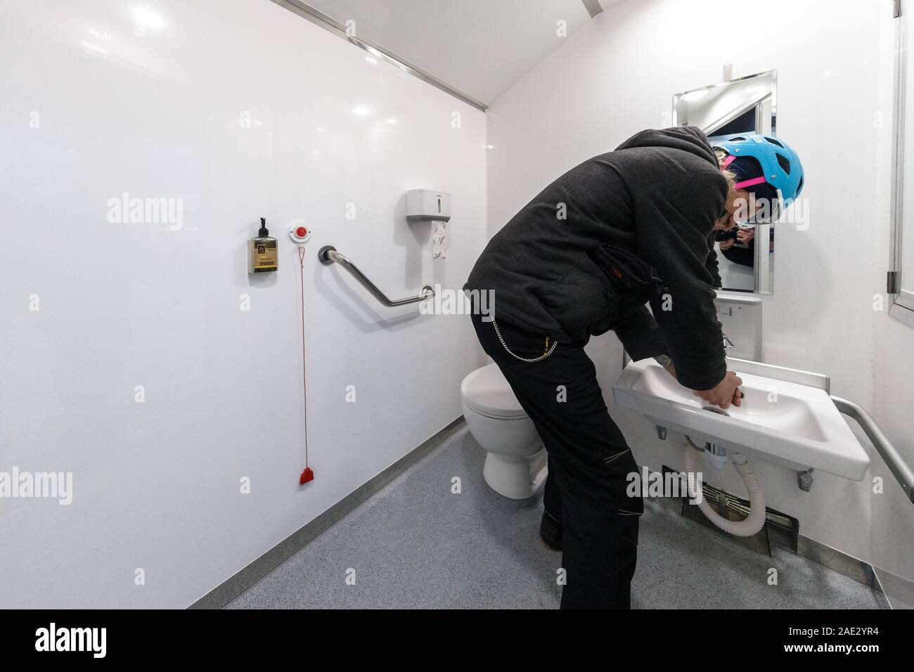 Hamburg, Germany. 06th Dec, 2019. A man washes his hands in the GoBanyo shower bus. The bus, a crowdfunded project, offers three washrooms and showers for the homeless. Credit: Markus Scholz/dpa/Alamy Live News Stock Photo