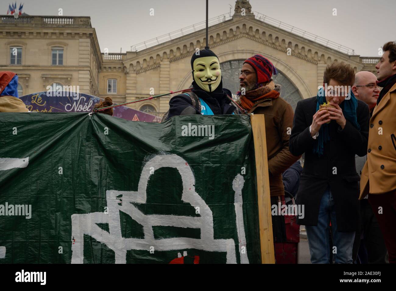 PARIS, FRANCE, DECEMBER 05 2019 : a firefighter taking part in the 'Gilets Jaunes' (Yellow Vests) protest and wearing an Anonymous mask. Stock Photo
