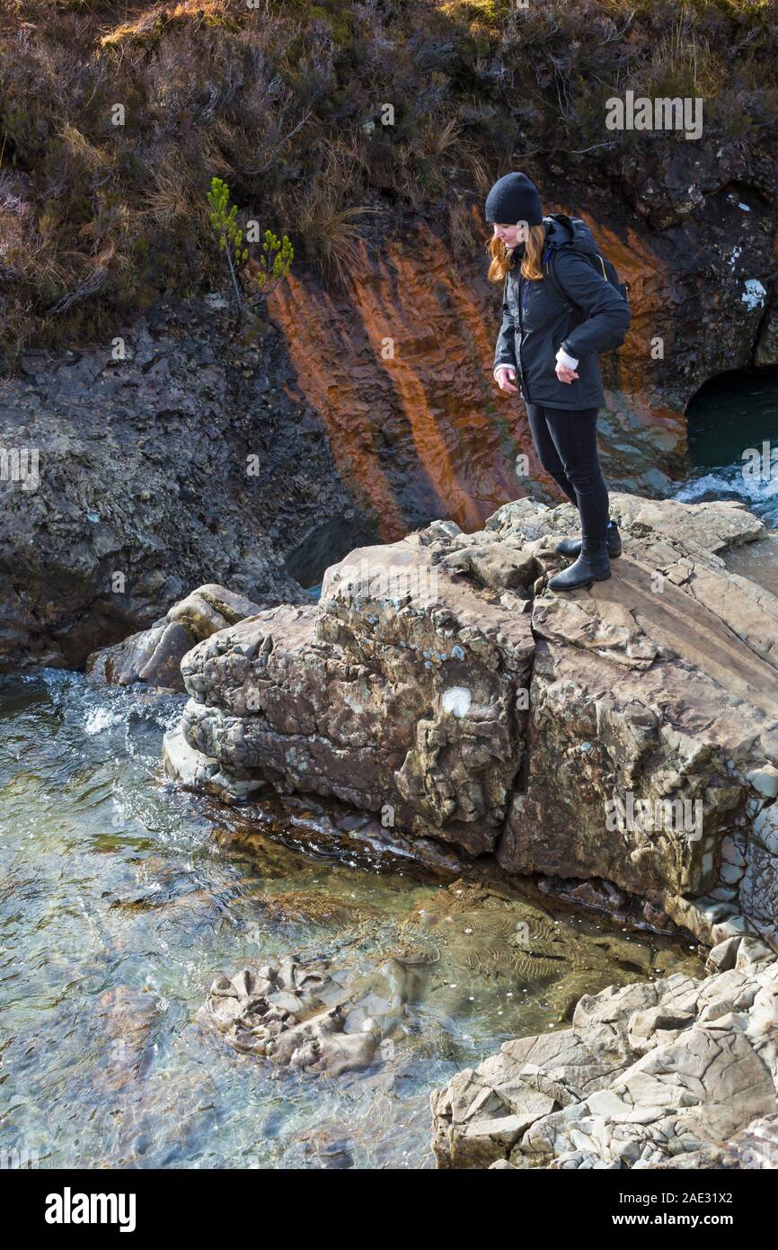 Young woman standing on rocks at Fairy Pools, river Brittle, Isle of Skye, Scotland, UK in March Stock Photo