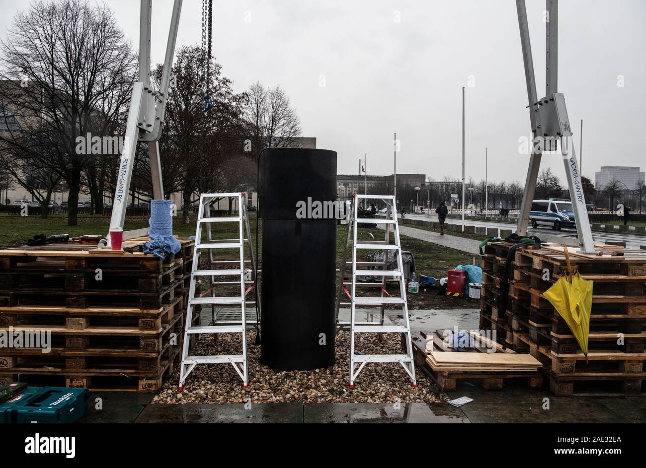 Berlin, Germany. 06th Dec, 2019. Wooden pallets, a column and a lifting device stand on a meadow not far from the Reichstag. The artists' collective 'Zentrum für politische Schönheit' (ZPS) had set up a controversial art installation there, which also included a column in which, according to ZPS information, the ashes of Holocaust victims could be seen. Since noon, members of the ZPS have been dismantling the installation. Credit: Paul Zinken/dpa/Alamy Live News Stock Photo