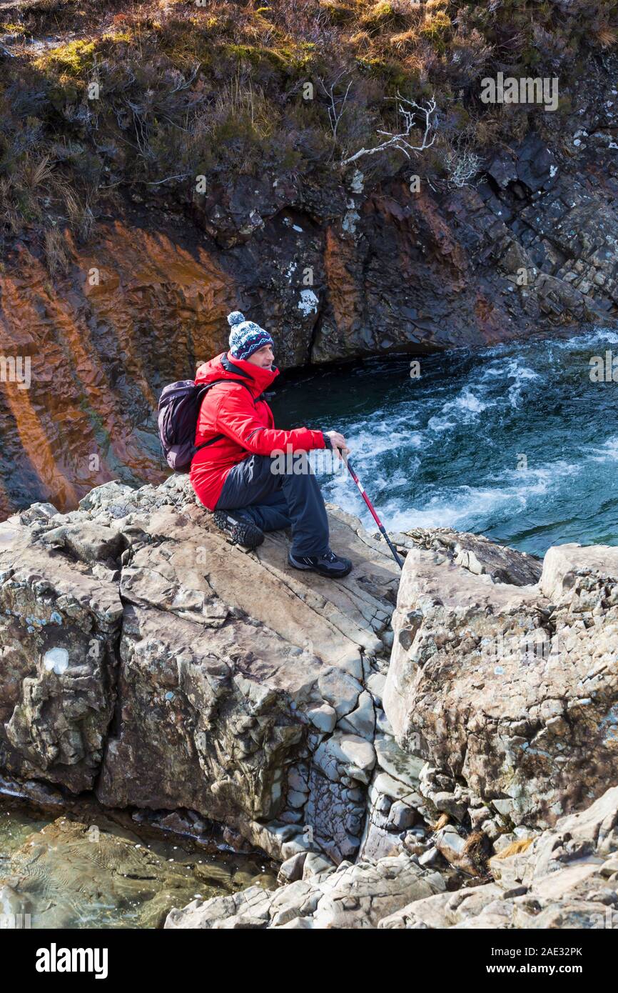 Man sitting on rocks at Fairy Pools, river Brittle, Isle of Skye, Scotland, UK in March Stock Photo