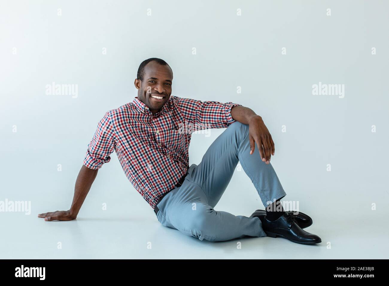 Delighted afro american man sitting on the floor Stock Photo