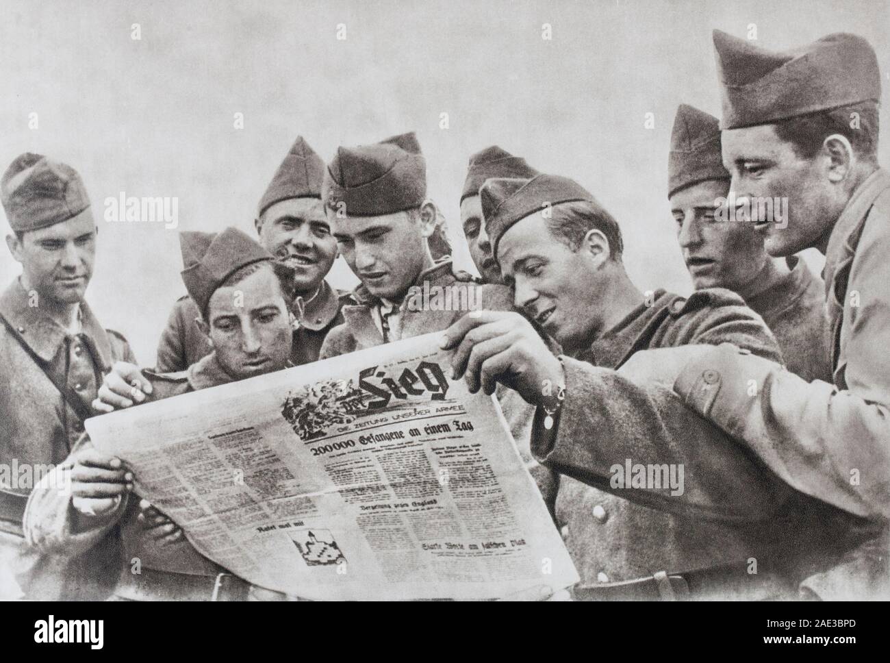 In the Stalags, we were on the lookout for all the news. French soldiers try to read a German newspaper. Stock Photo