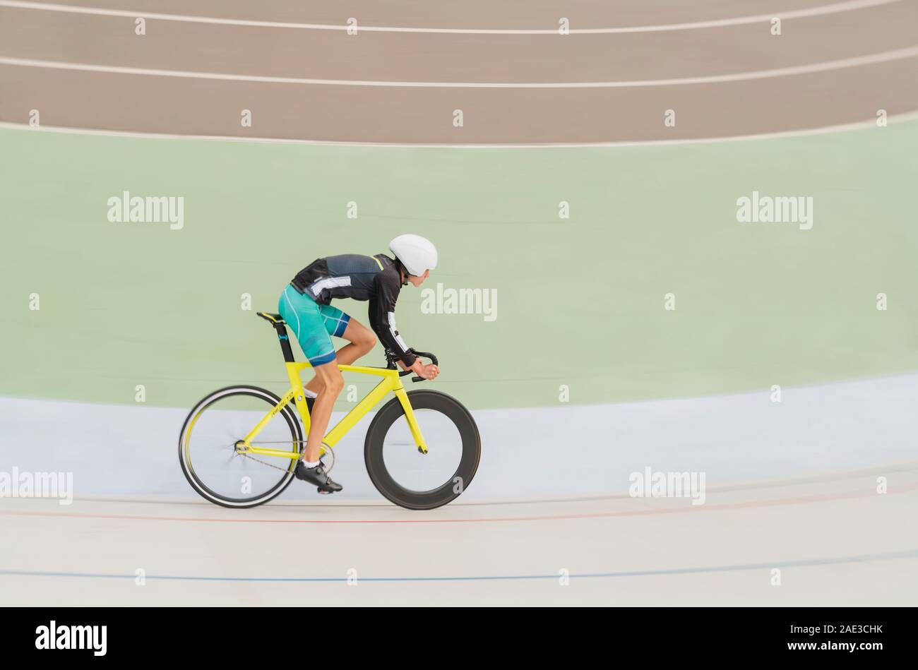 Young man cyclist rides on bike track in athletic wear and helmet at high speed during  bicycling sports competition, close up. Horisontal image. Stock Photo
