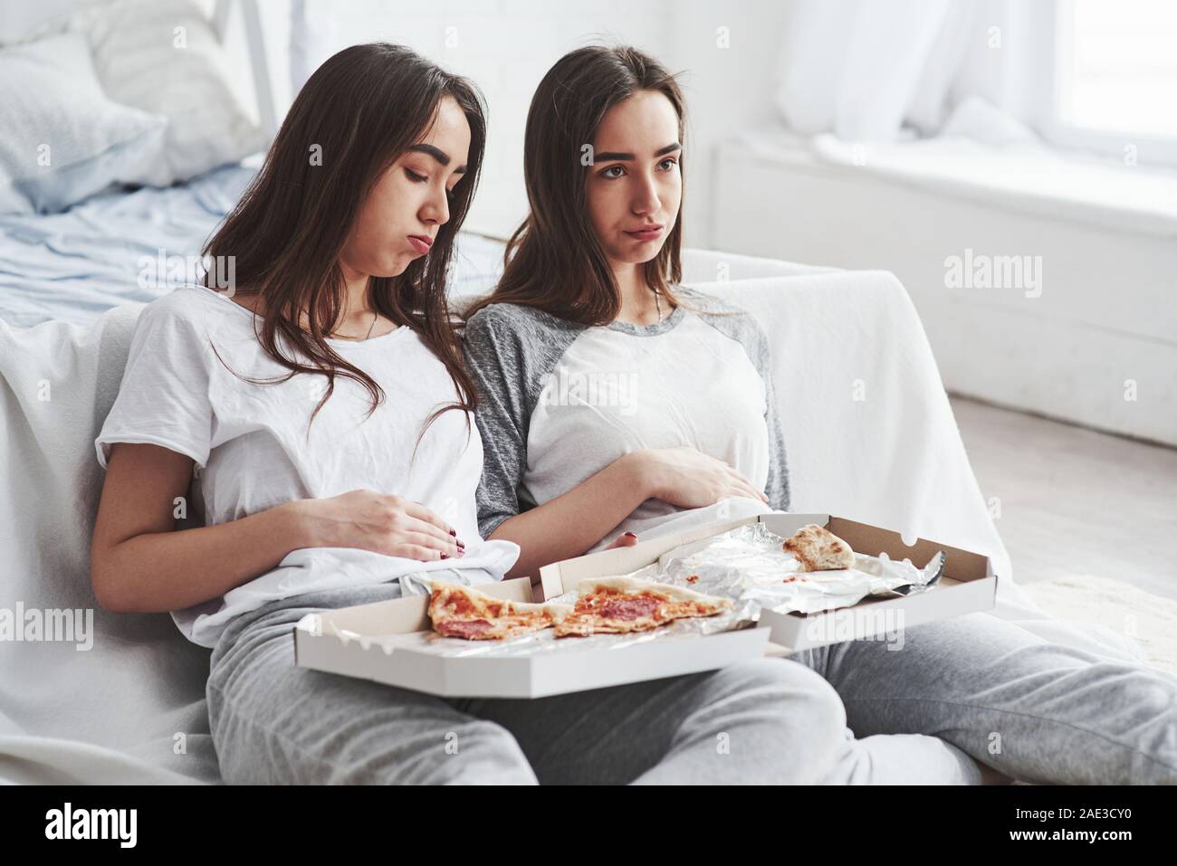 I don't expected that this will go that way. Twins have full stomach with pizza. Nice bedroom at daytime Stock Photo