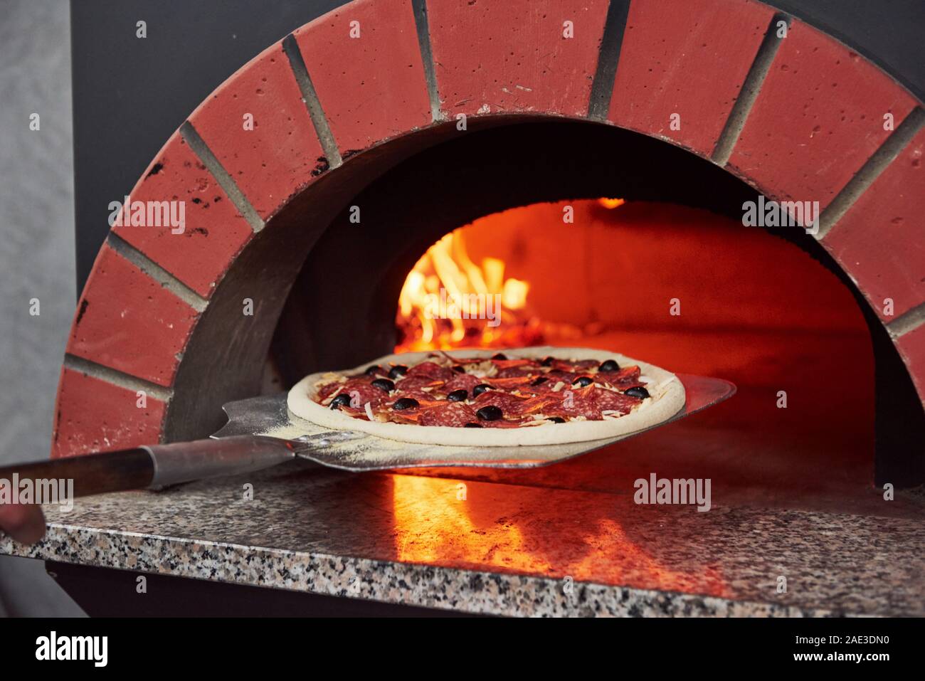Putting pizza inside. Fire burning in the furnace. Close up view of