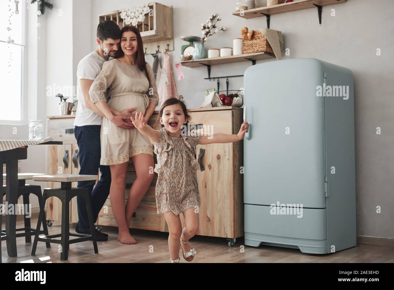 Happy family. Playful female child have fun by running in the kitchen