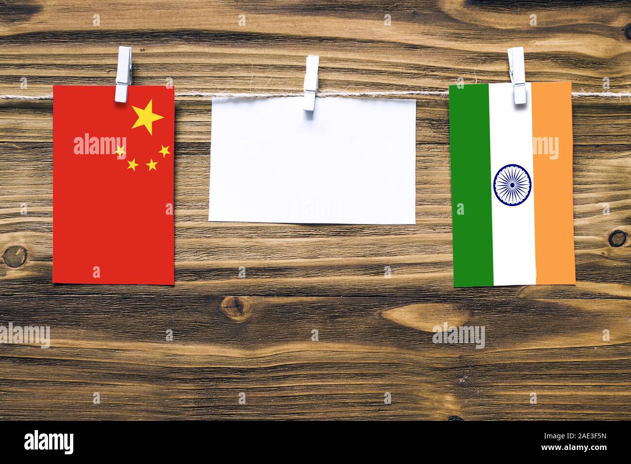 Hanging flags of China and India attached to rope with clothes pins with copy space on white note paper on wooden background.Diplomatic relations betw Stock Photo