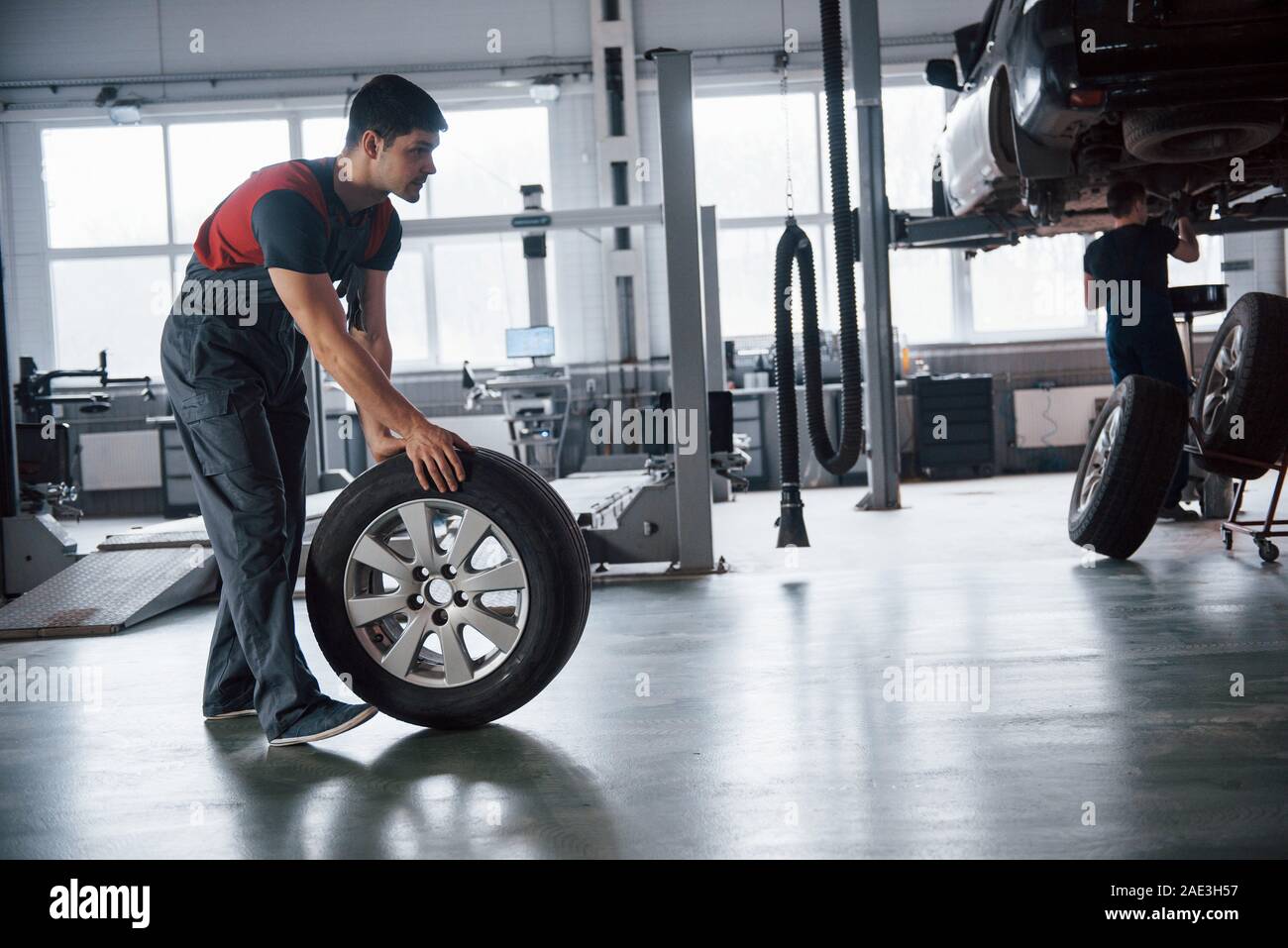 One more guy works on the crased vehicle. Mechanic holding a tire at