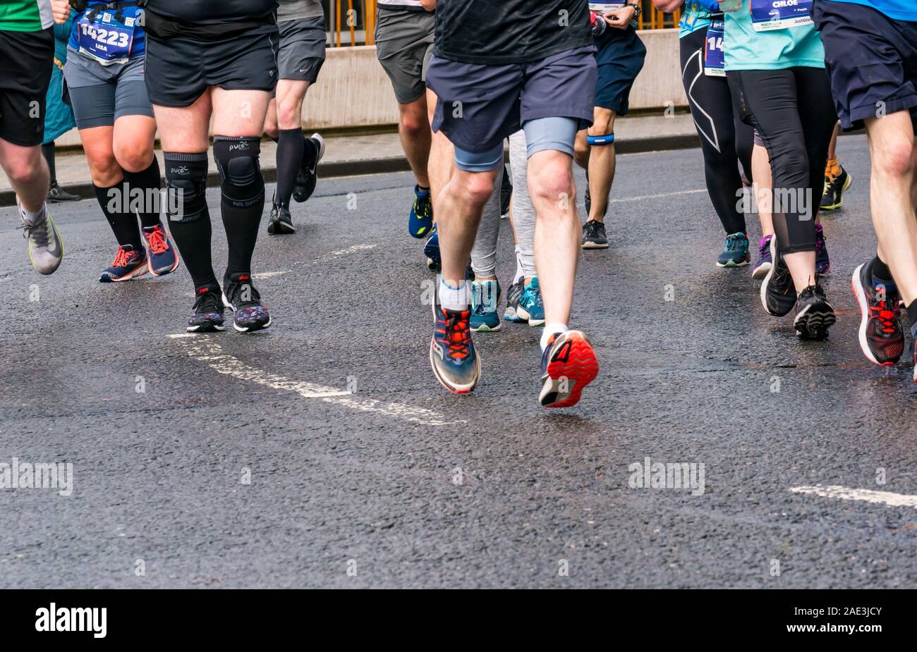 Close up runners legs feet & running shoes on wet tarmac road, Edinburgh Marathon Festival 2019, Scotland, UK Stock Photo