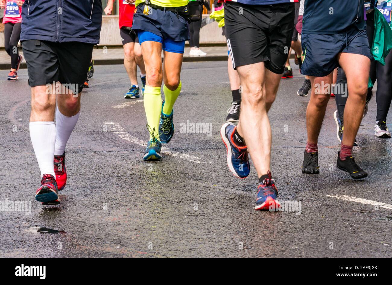 Close up runners legs feet & running shoes on wet tarmac road, Edinburgh Marathon Festival 2019, Scotland, UK Stock Photo