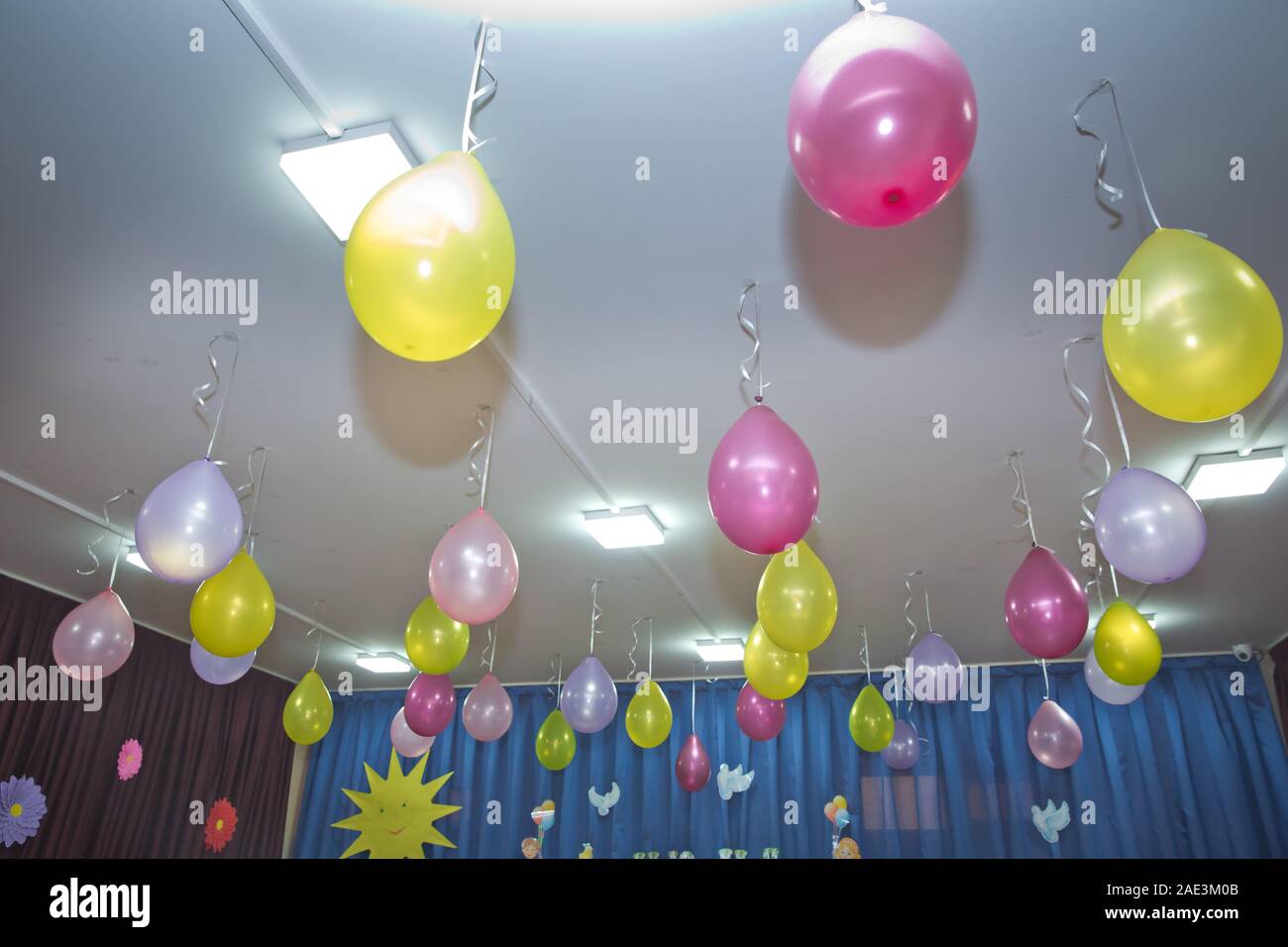 Pink And Yellow Balloons Float On The White Ceiling In The Room