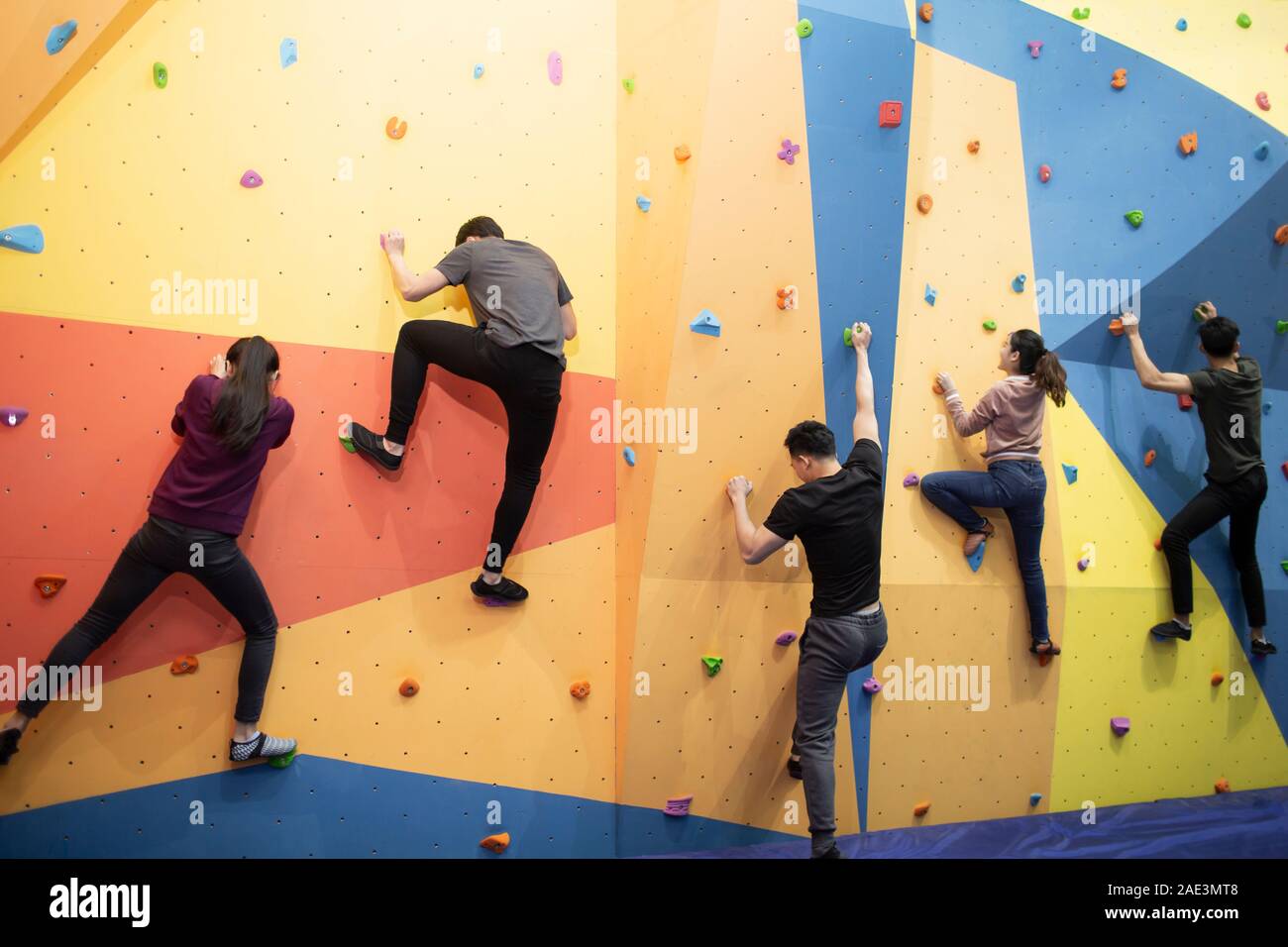 Young friends climbing a climbing wall at gym Stock Photo Alamy