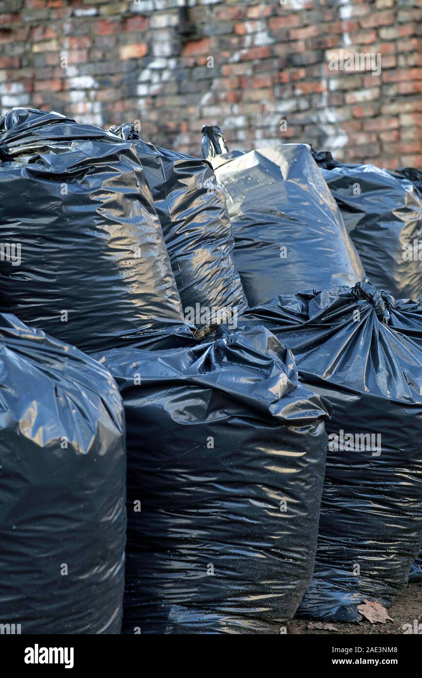 Big pile of black plastic garbage bags with trash stacked on the street