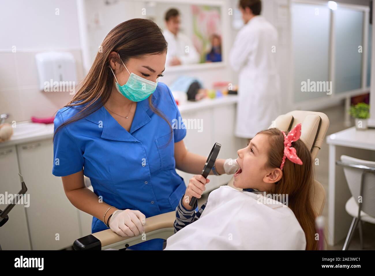 Child in dental chair hold magnifying glass near open mouth Stock Photo