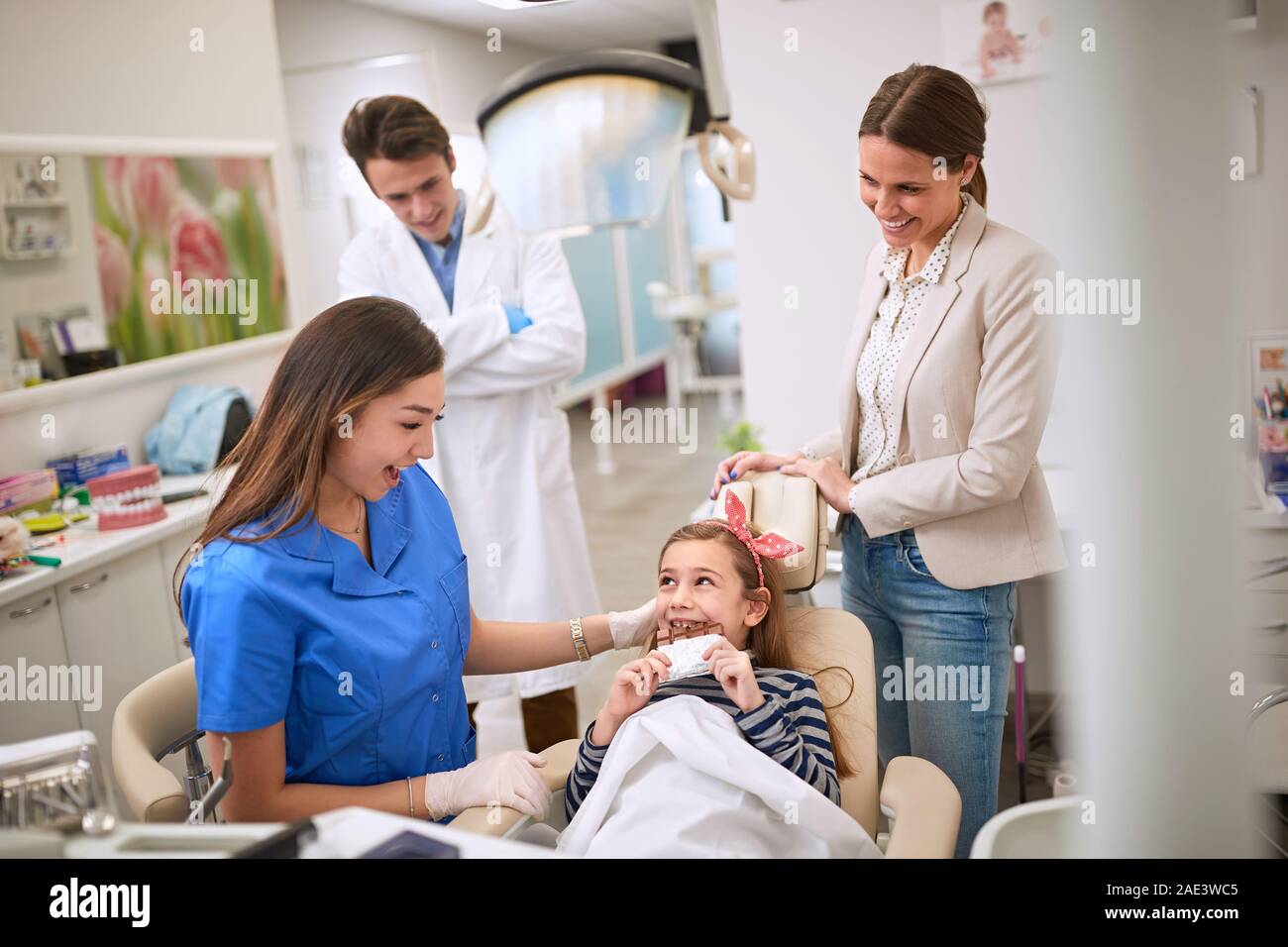 Happy girl in dental chair eating chocolate Stock Photo
