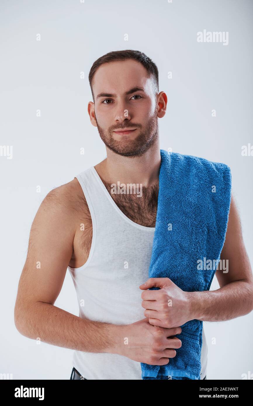 Going to the shower. Man with blue towel stands against white