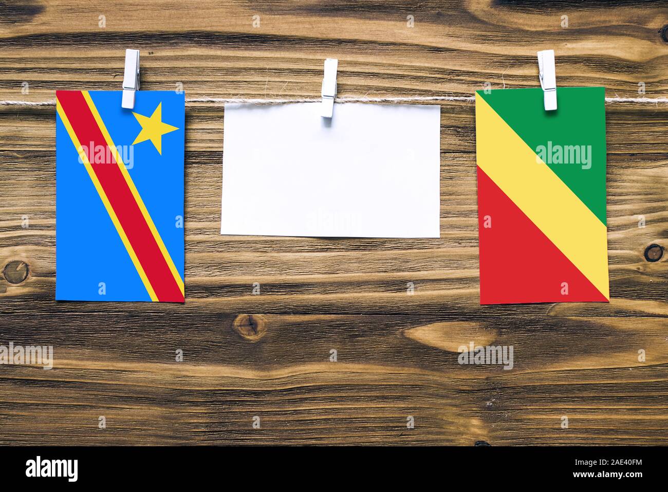 Hanging flags of Congo and Republic Of The Congo attached to rope with clothes pins with copy space on white note paper on wooden background.Diplomati Stock Photo