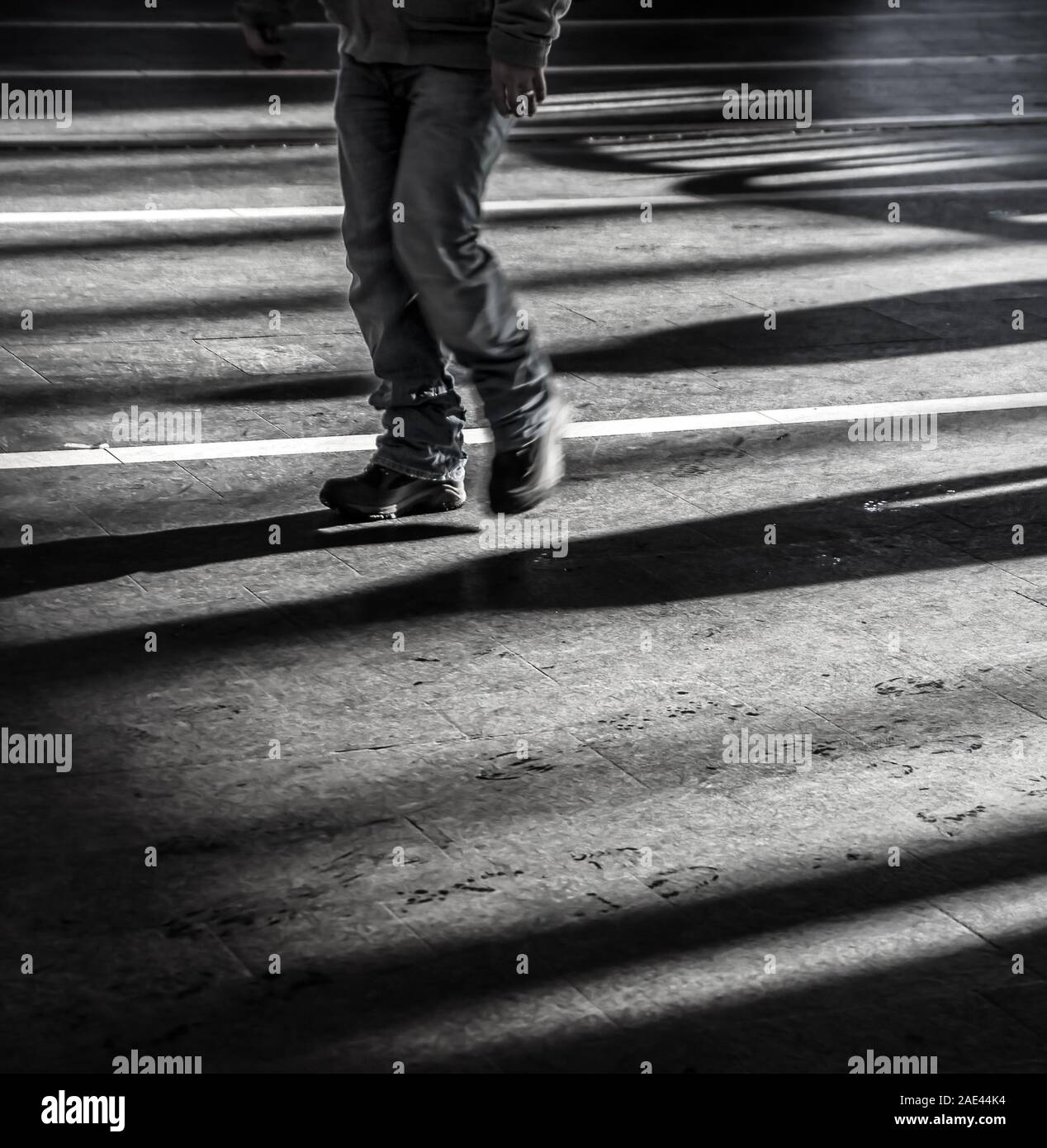 Black young man walking alone in urban city with light and dark shadows - Concept of loneliness, outsider or feeling sad and depressed. Stock Photo