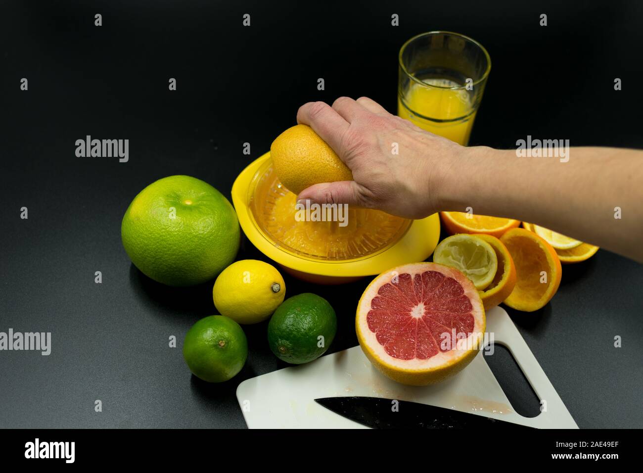 Hand squeezes grapefruit in juicer. On black background Stock Photo