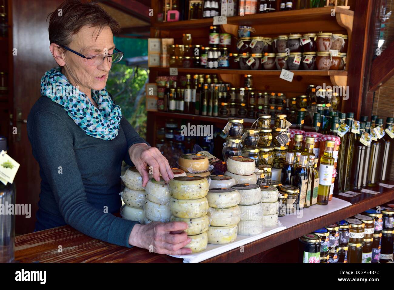 Older woman working in family roadside farm produce stall selling olive oil, cheese and produce, stall Panorama Limski Fjord, D75 road, Istria, Croati Stock Photo