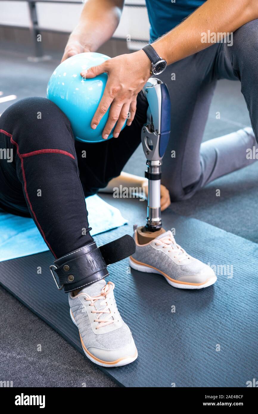 Personal trainer assisting woman with disabilities in her workout ...