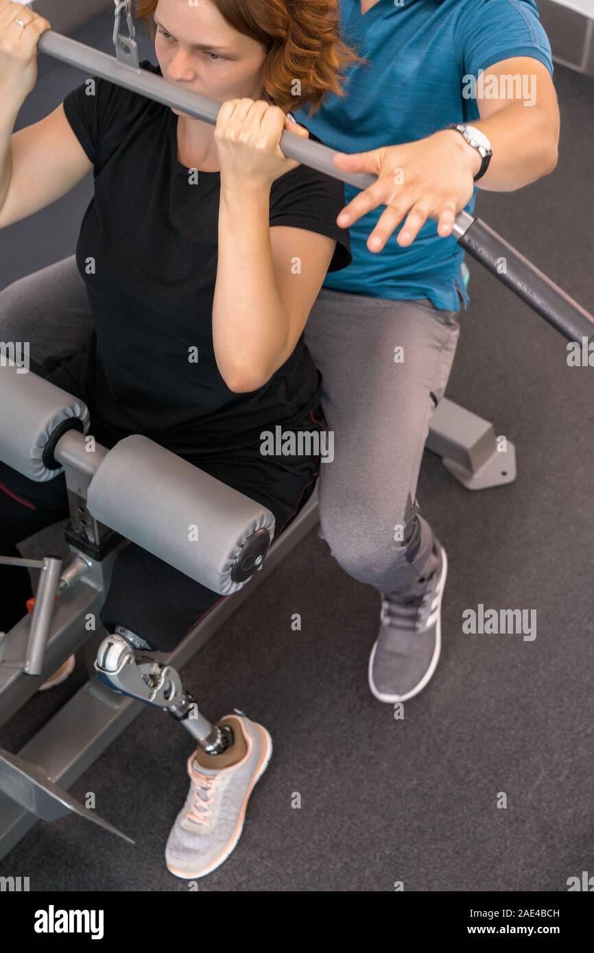 Personal trainer assisting woman with disabilities in her workout ...
