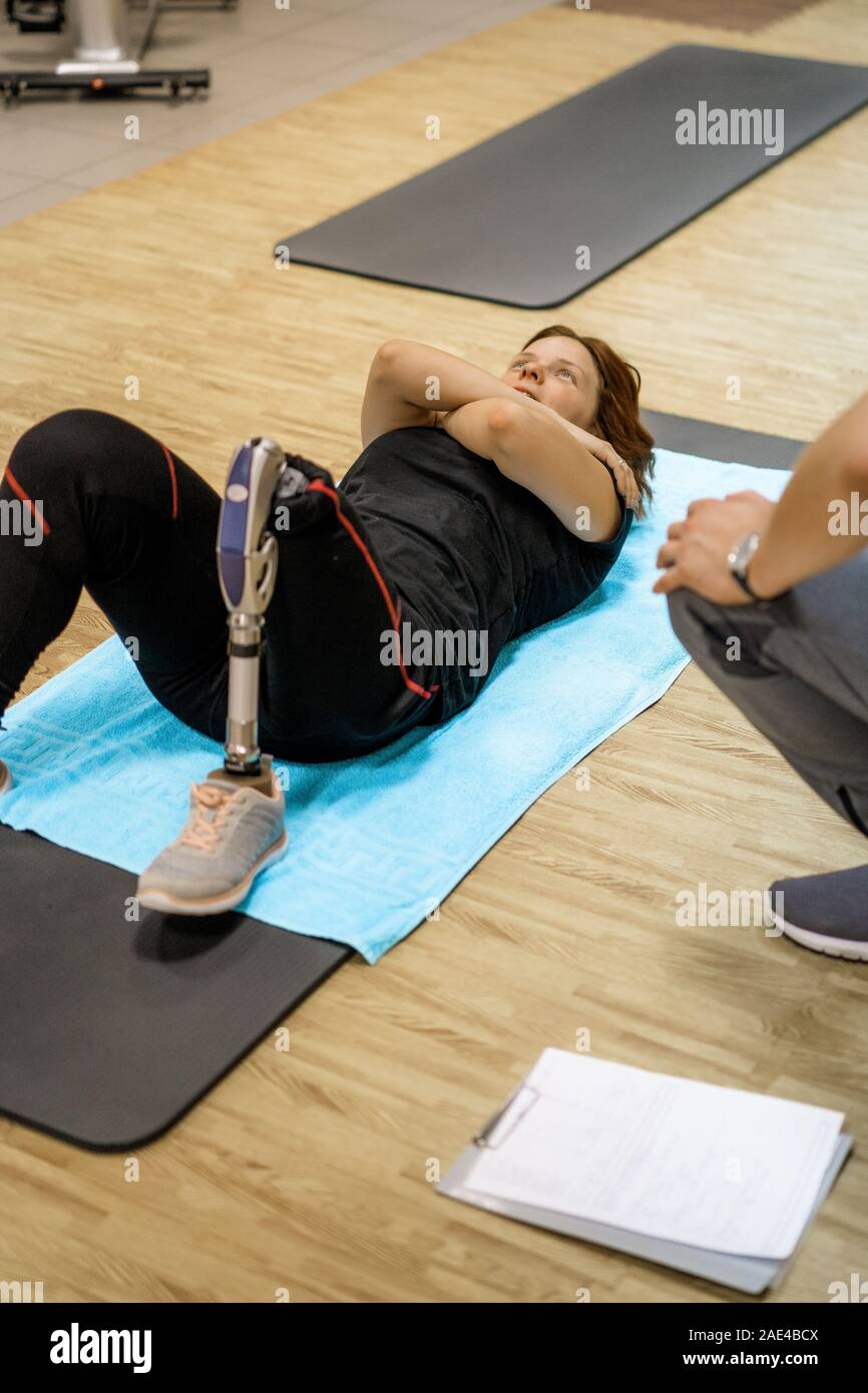 Personal trainer assisting woman with disabilities in her workout ...