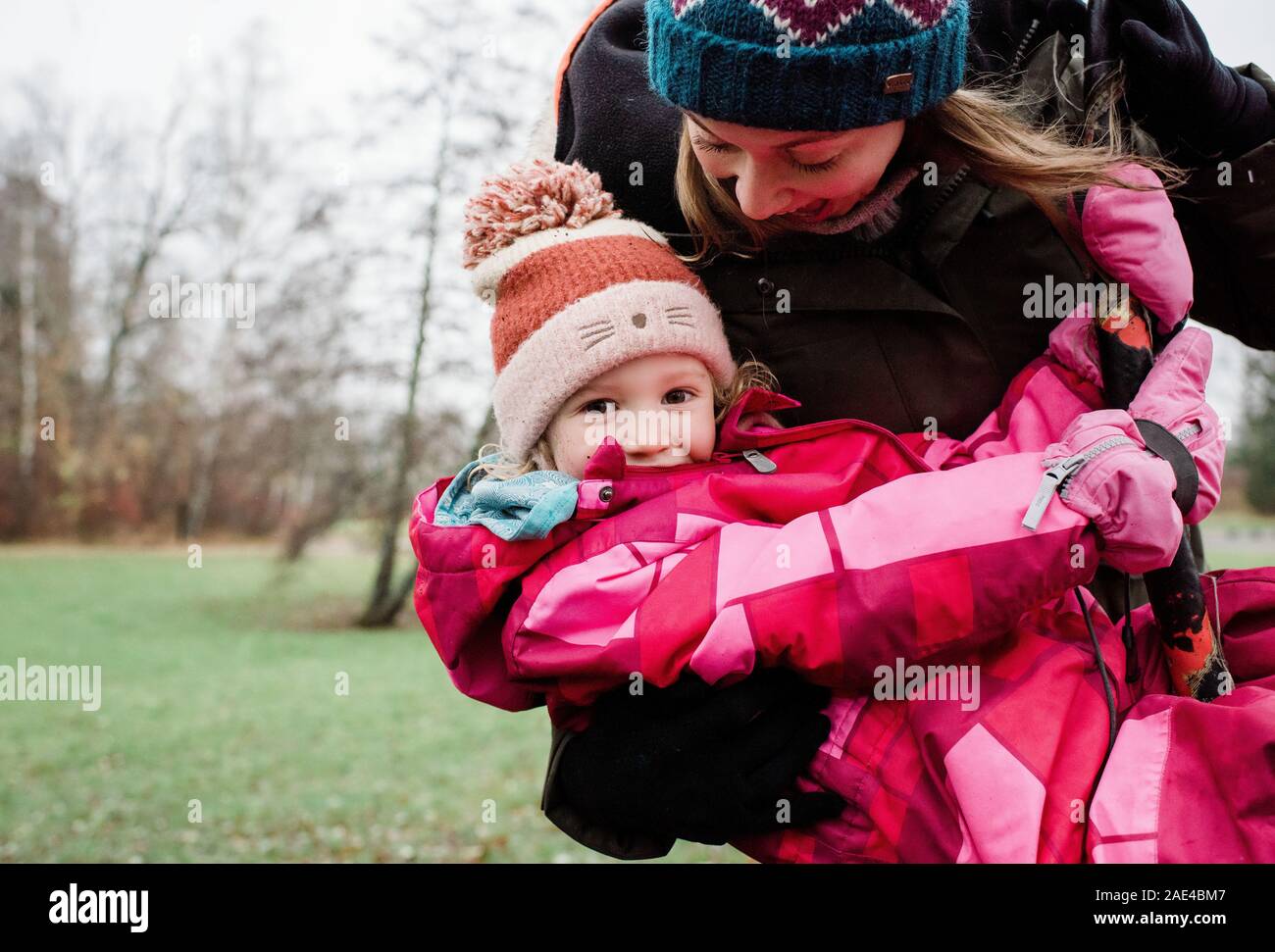 mother playing with her daughter on a swing outside in winter Stock Photo