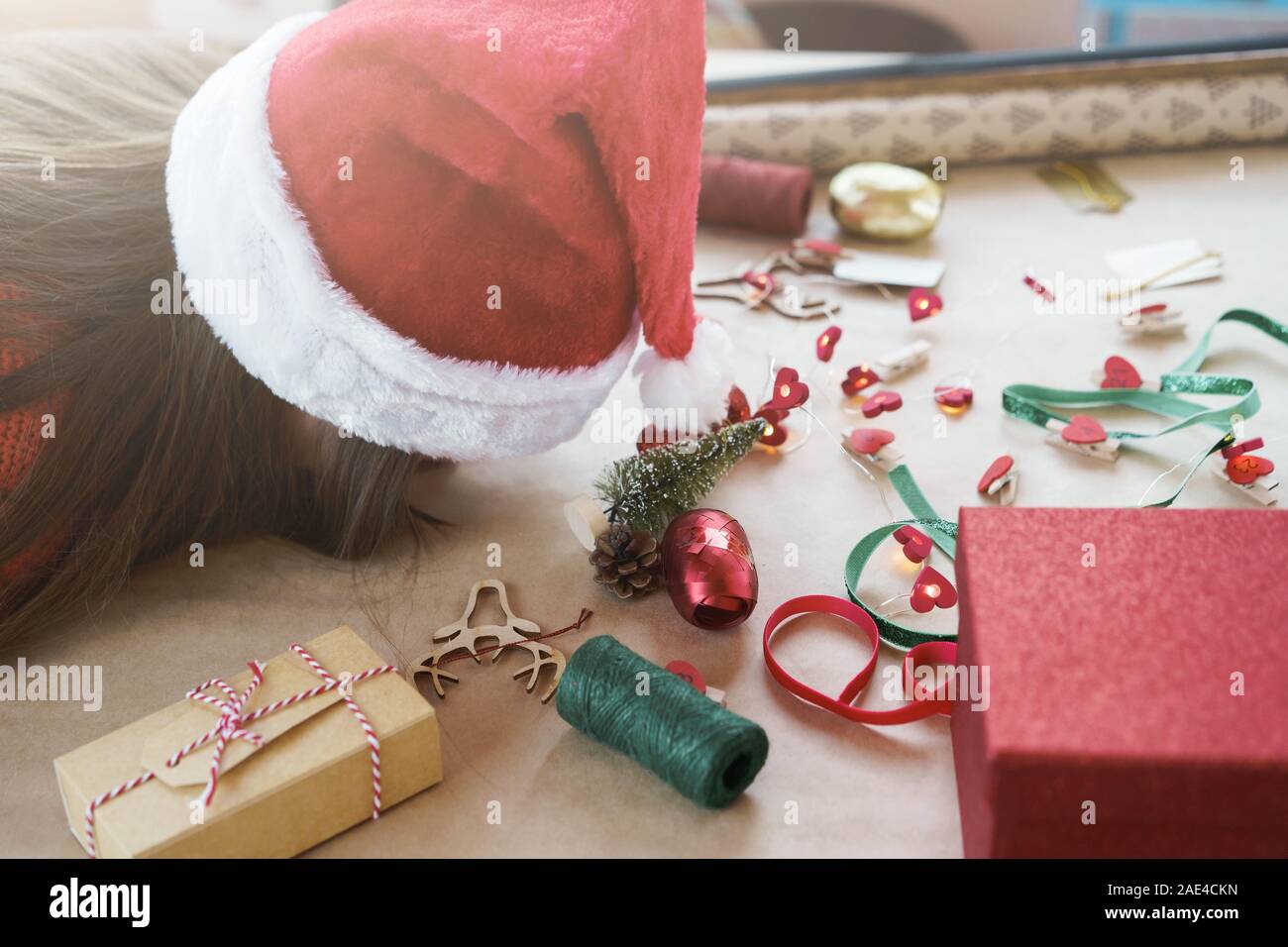 A girl in red pullover and Santa Claus hat slipping on the table Stock Photo