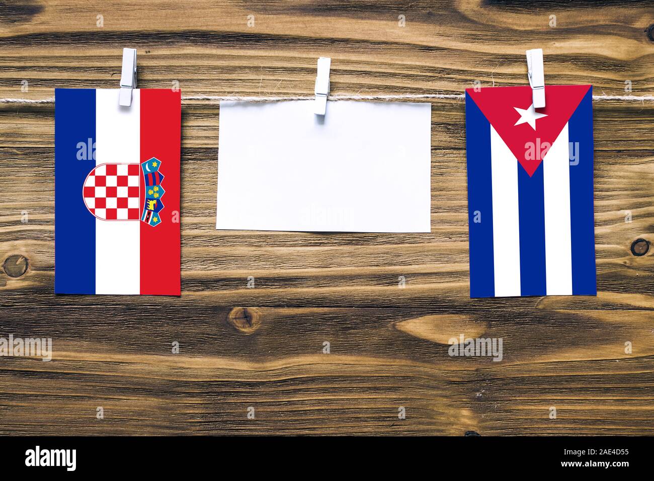 Hanging flags of Croatia and Cuba attached to rope with clothes pins with copy space on white note paper on wooden background.Diplomatic relations bet Stock Photo