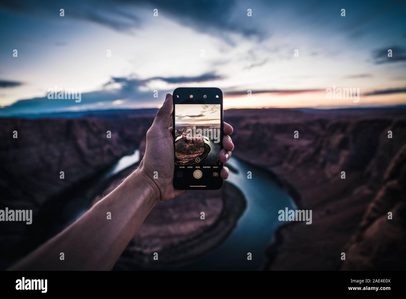 Young Man holding iPhone, photographing sunset at Horseshoe Bend Stock Photo