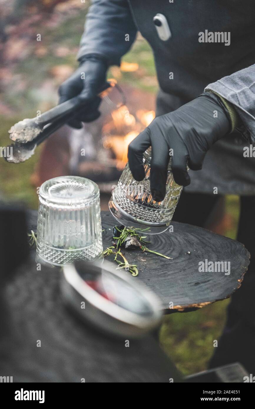 Someone smokes a glass with a lump of charcoal to make a smoky cocktai Stock Photo