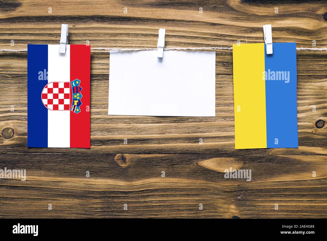 Hanging flags of Croatia and Ukraine attached to rope with clothes pins with copy space on white note paper on wooden background.Diplomatic relations Stock Photo