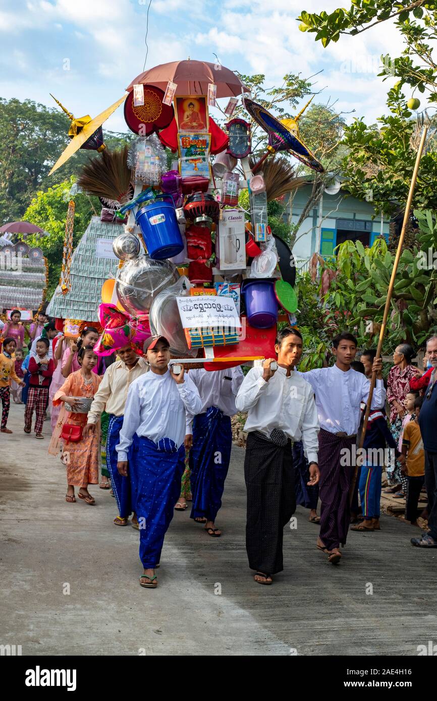 The men of a Burmese village carry a float in a parade/procession to honor the monks of their village with donations in rural Myanmar (Burma) Stock Photo