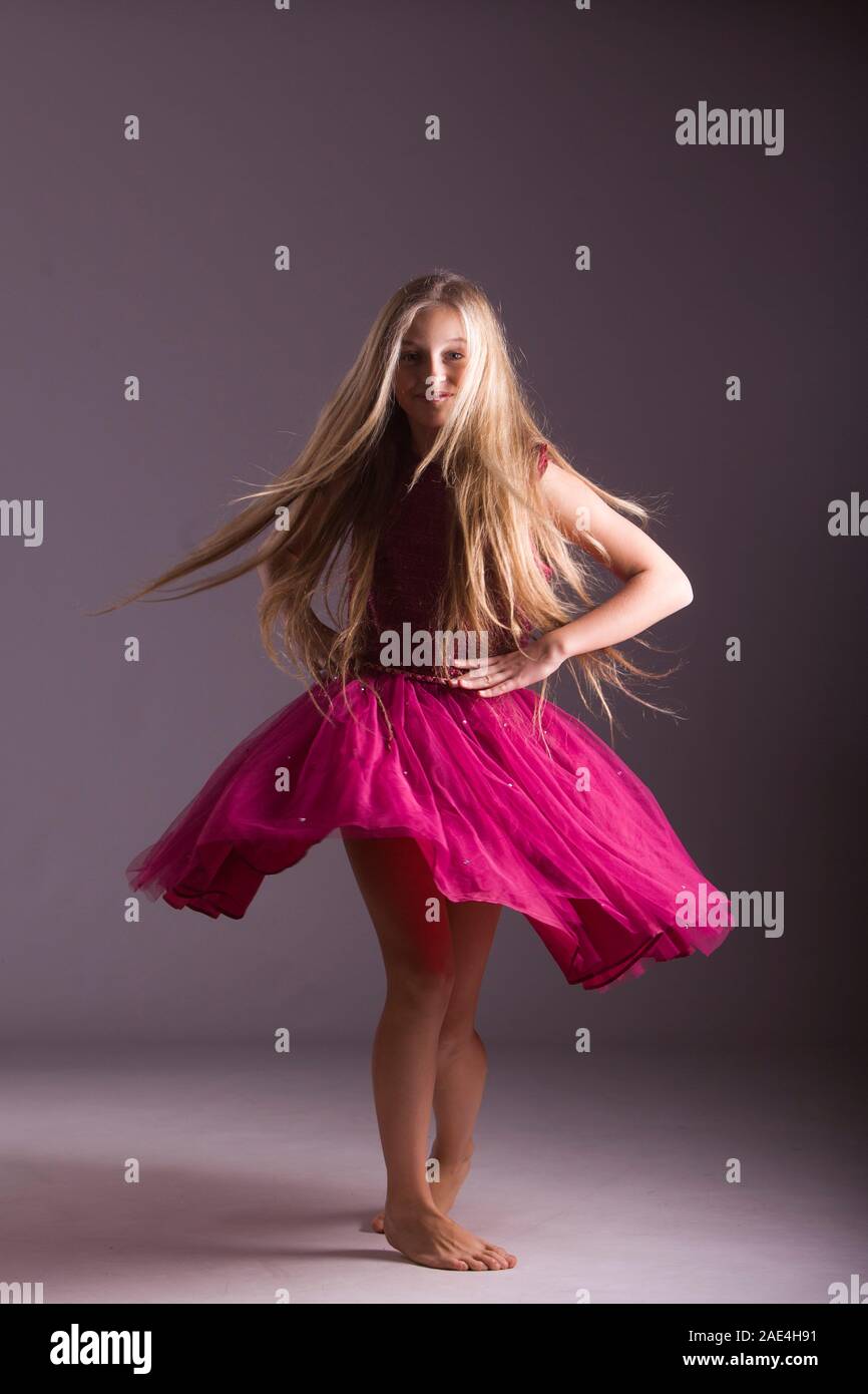 Portrait of long haired blonde girl in pink dress shot in studio on white background Stock Photo