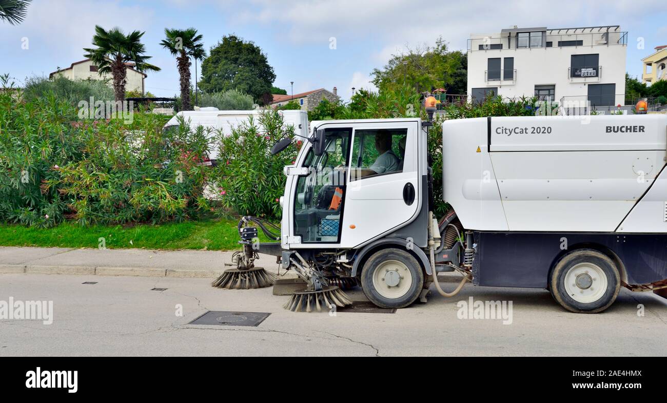 Small Bucher CityCat 2020 municipal street sweeping truck with brushes working in small town of Vrsar, Croatia Stock Photo