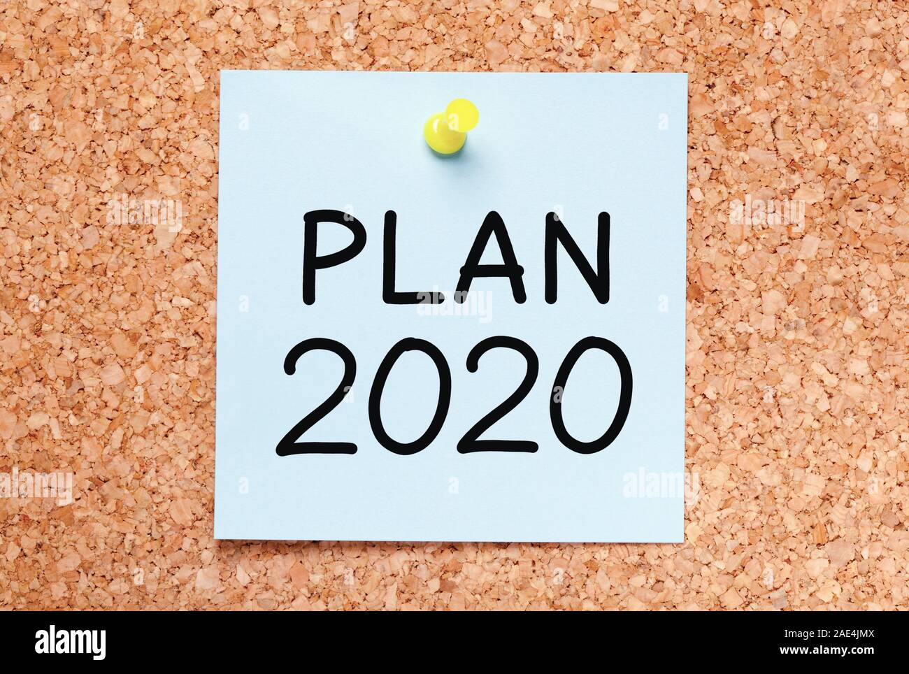 Text Plan for year 2020 handwritten on blue sticky note pinned on cork bulletin board. Stock Photo