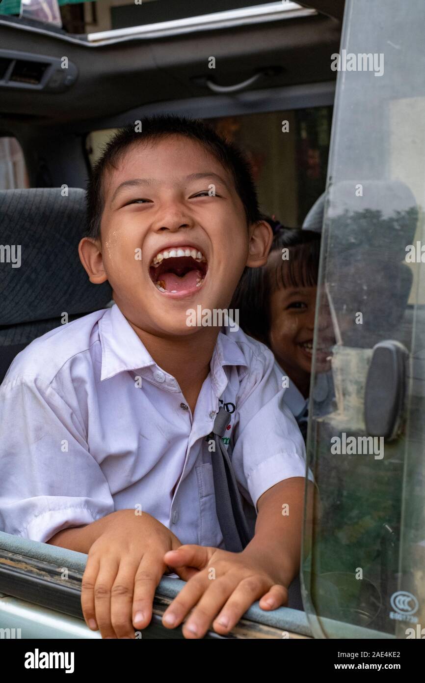 Young Burmese boy roars with laughter while sitting in a bus and looking out the window in Homalin, Myanmar (Burma) Stock Photo