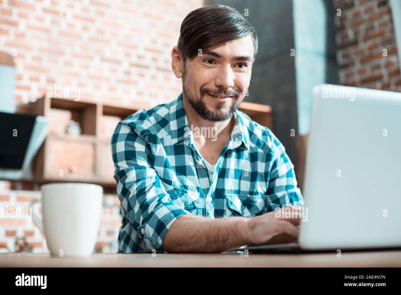 Nice positive man working on a laptop Stock Photo