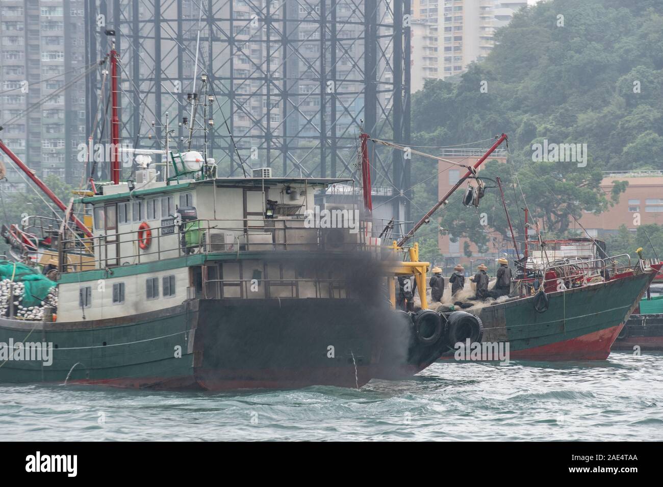 Heavy, black smoke and exhaust spews from Industrial fishing boats and trawlers in Hong Kong Island's Aberdeen Harbour Stock Photo