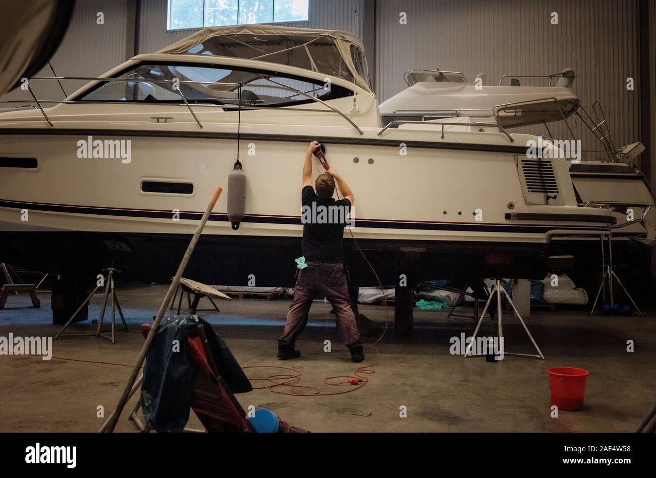 Marine technician engineer polishing a yacht boat in a warehouse Stock