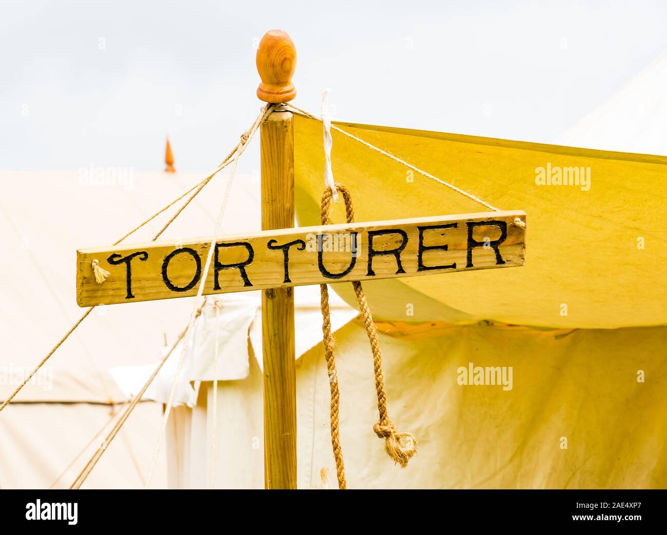 Humorous wooden sign with Torturer outside tent at Medieval village fair, Scotland, UK Stock Photo