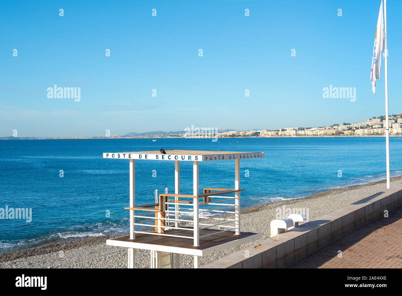 A black pigeons sits atop a Poste de Secours, or First Aid Station on the empty beach of the Bay of Angels on the French Riviera in Nice, France. Stock Photo