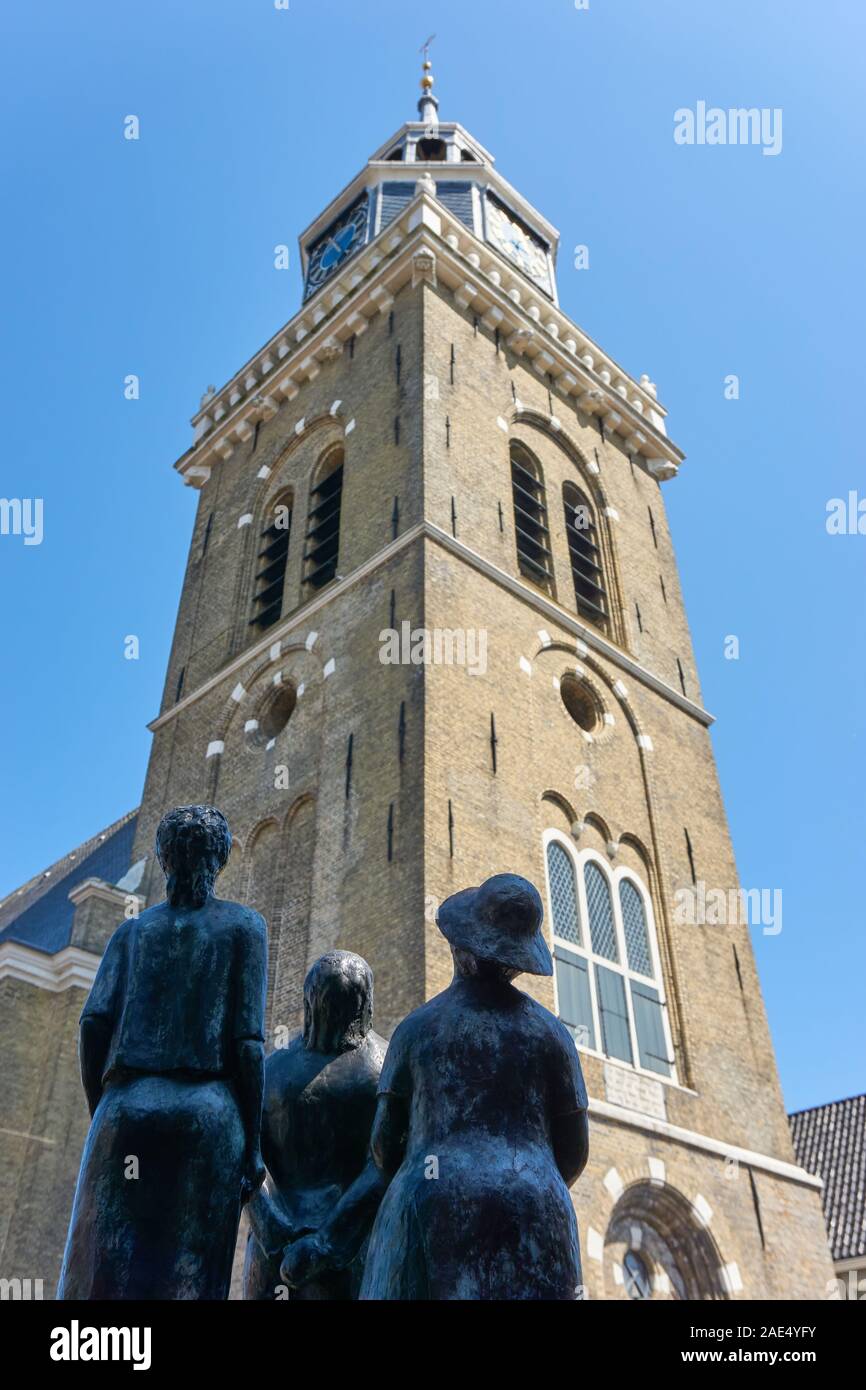 Low view on the Jouster Toren or Jouster Toer in Joure against a blue sky. In front a bronze sculpture of people looking at it. Stock Photo