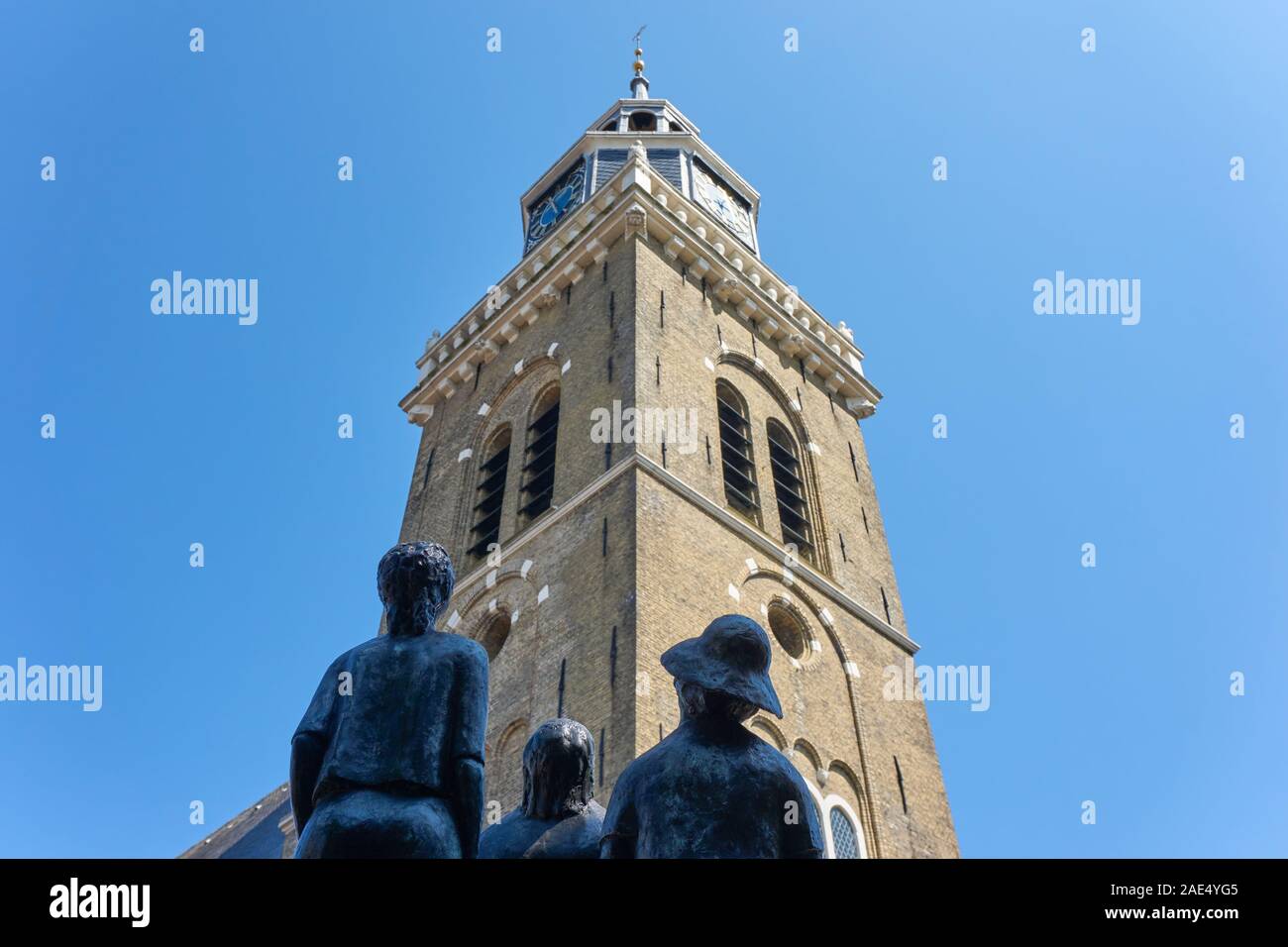 Low view on the Jouster Toren or Jouster Toer in Joure against a blue sky. In front a bronze sculpture of people looking at it. Stock Photo