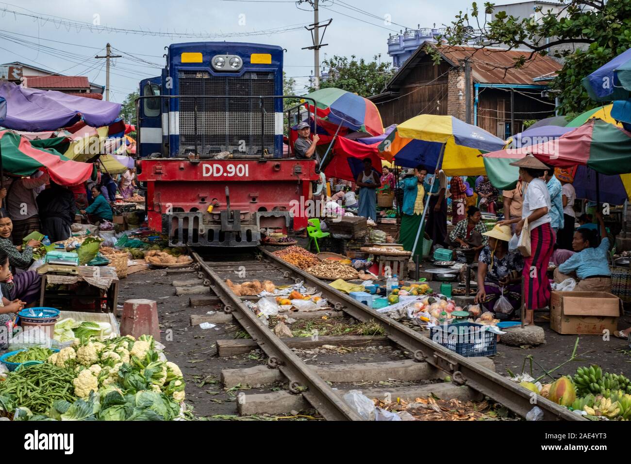 The railroad marketplace on the tracks of a local railroad with mobile market stalls, vendors and umbrellas in Mandalay, Myanmar (Burma) Stock Photo