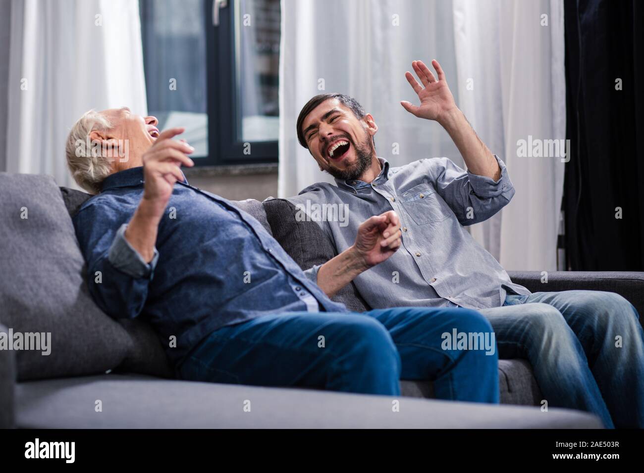 Overjoyed son and elderly father making jokes Stock Photo