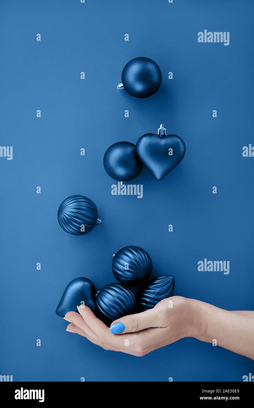Female hand juggling blue Christmas round balls and heart shape. Stock Photo