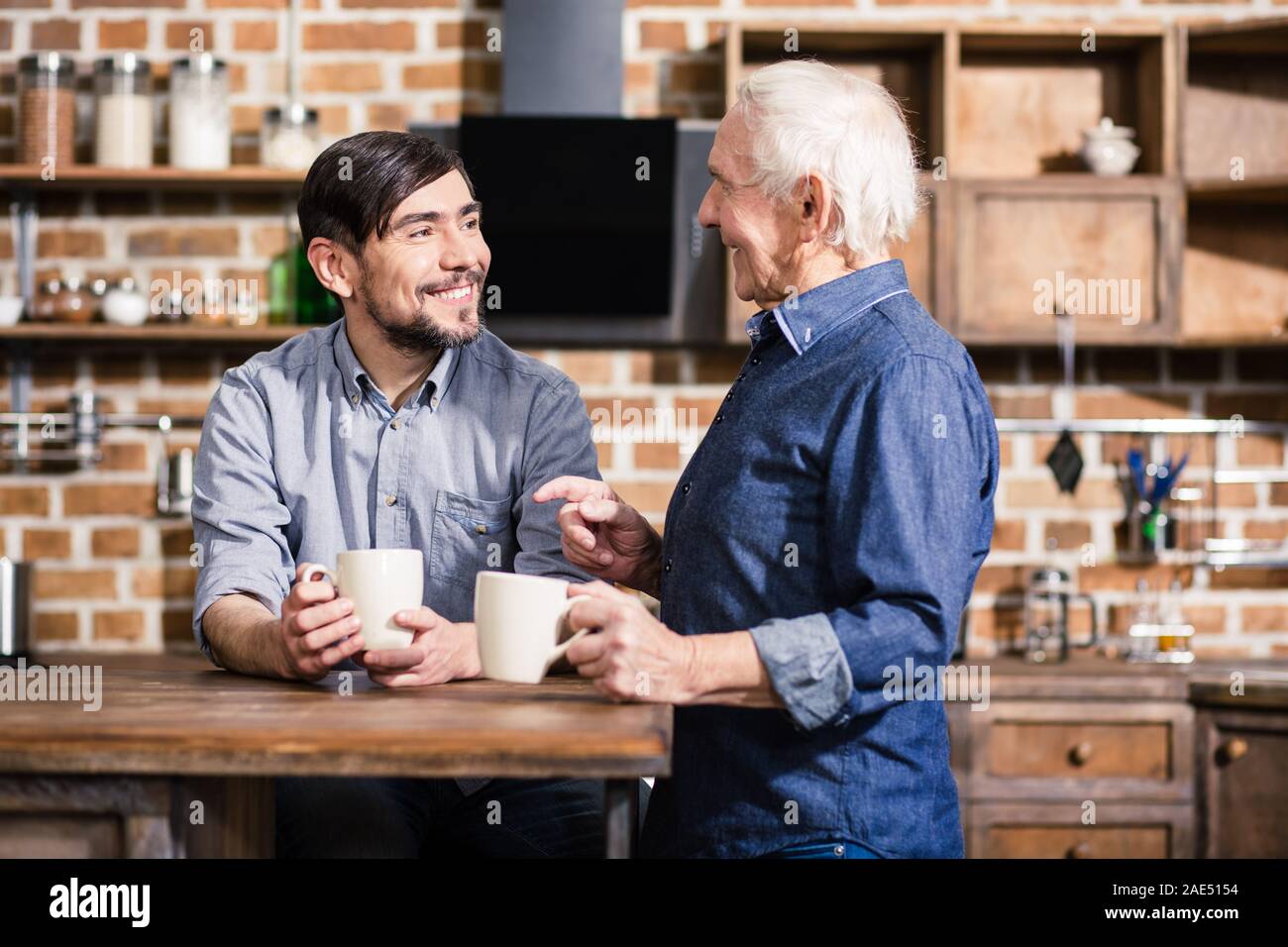 Pleasant smiling man drinking tea with his son Stock Photo